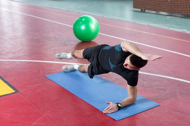 Ragazzo atletico in abbigliamento sportivo e fitness tracker facendo esercizi in palestra.