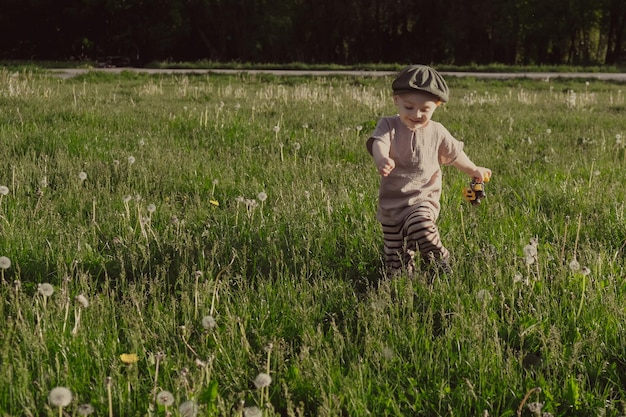 Ragazzo attivo del bambino felice che corre intorno al campo estivo in campagna