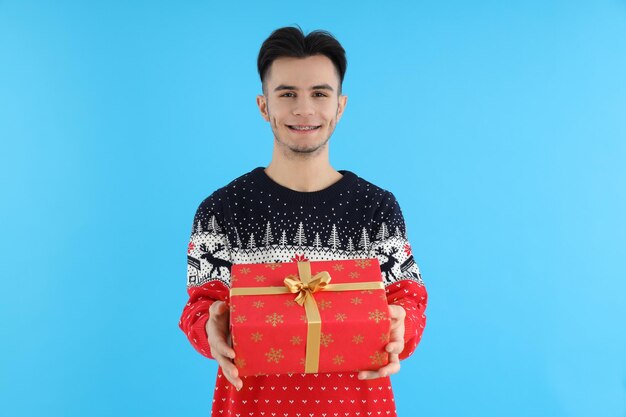 Ragazzo attraente con regalo di Natale su sfondo blu