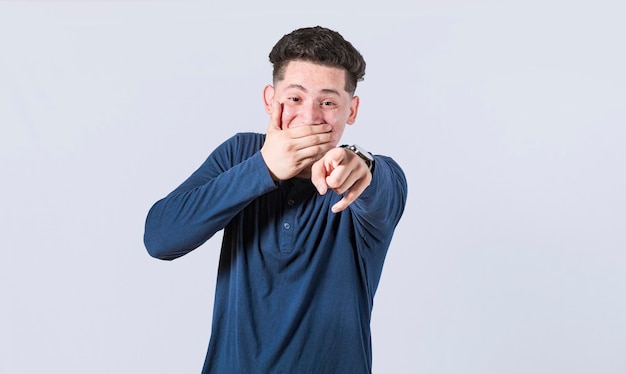 Ragazzo attraente isolato ridere di te Un uomo che punta alla telecamera con la mano sulla bocca maschio prendere in giro di te