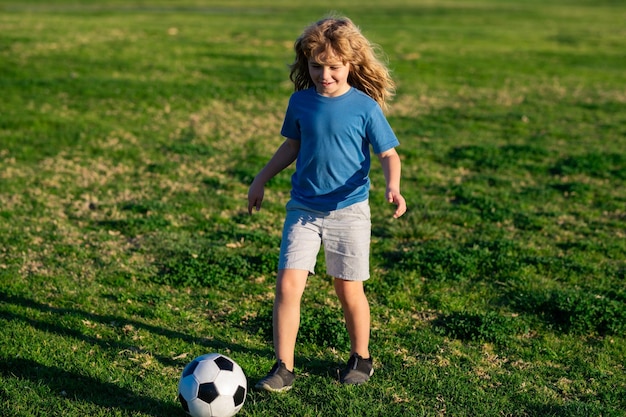 Ragazzo bambino che gioca a calcio sul campo di calcio bambino che gioca a calcio bambino che dà dei calci a un pallone da calcio su un'erba
