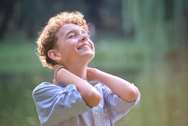 Ragazzo bambino felice che si rilassa nel parco estivo Bambino positivo che si gode l'estate all'aperto Concetto di benessere del bambino