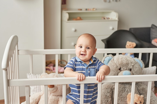 ragazzo bambino gioca giocattoli di legno in una stanza per bambini in colori vivaci, camera da letto per bambini in stile scandinavo