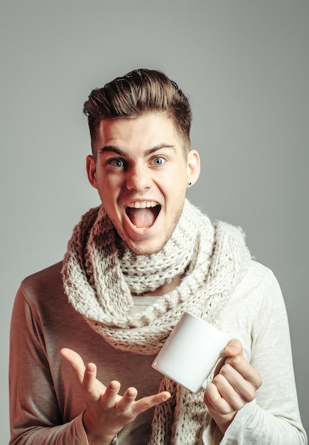 Ragazzo bello con la tazza in sciarpa