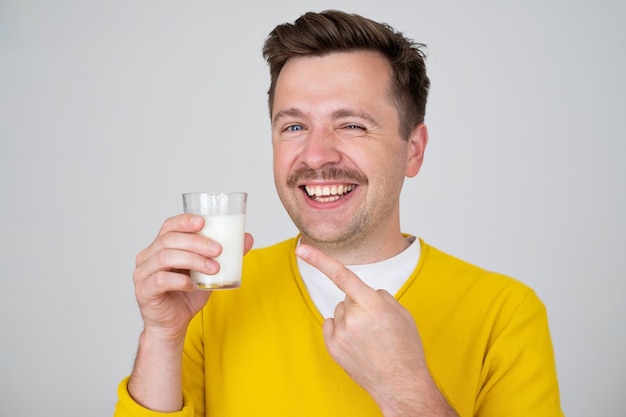 Ragazzo bello divertente sorridente 2 che posa tenendo in mano un bicchiere di latte
