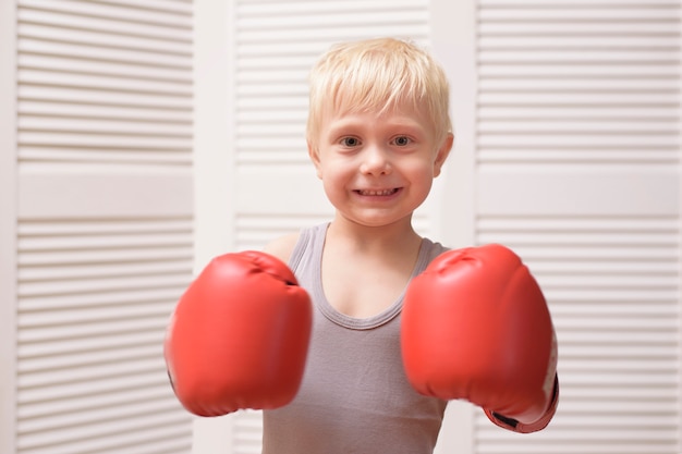 Ragazzo biondo adorabile in guantoni da pugile rossi. Gli sport