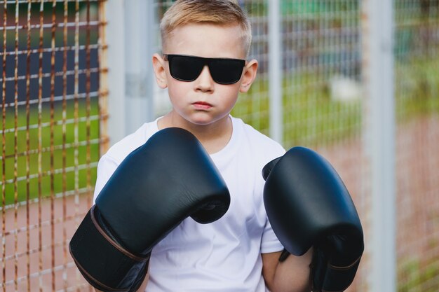 Ragazzo biondo in occhiali scuri e guantoni da boxe. Foto di alta qualità