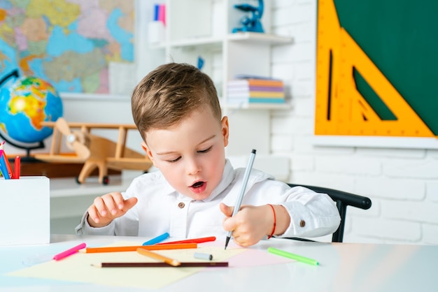 Ragazzo carino a casa o bambino all'asilo che studia da casa, apprendimento della scuola elementare e concetto di bambini