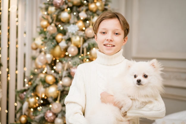 Ragazzo carino all'albero di natale con cane in attesa di buon natale ragazzo felice e cane l'abbracci...