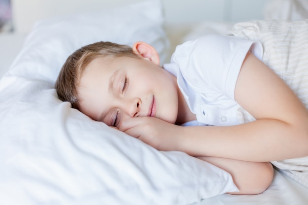 Ragazzo carino che dorme nel letto. Mattina.