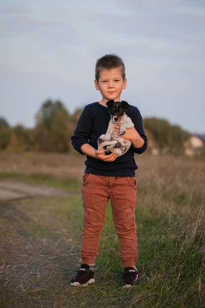 Ragazzo carino che gioca con il suo cane nel prato