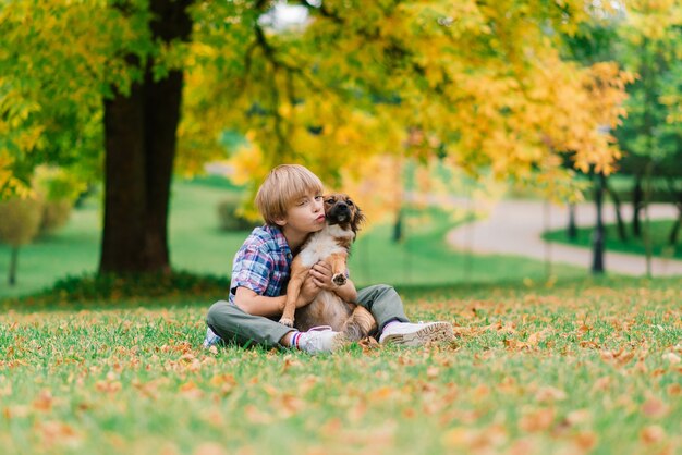 Ragazzo carino che gioca e cammina con il suo cane in un prato.