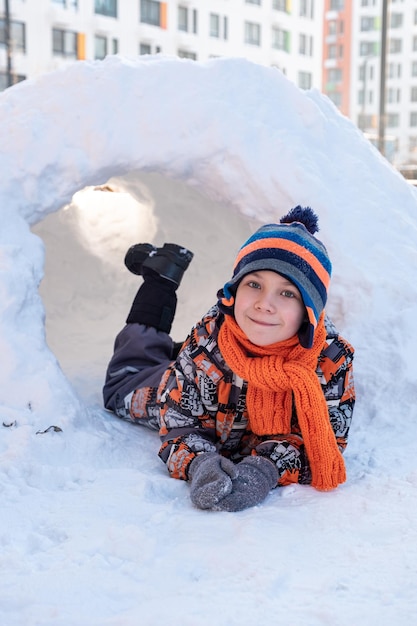 Ragazzo carino che gioca nell'igloo del castello di neve