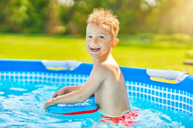 Ragazzo carino che nuota e gioca in una piscina nel cortile