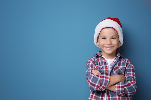 Ragazzo carino con cappello da Babbo Natale su sfondo colorato