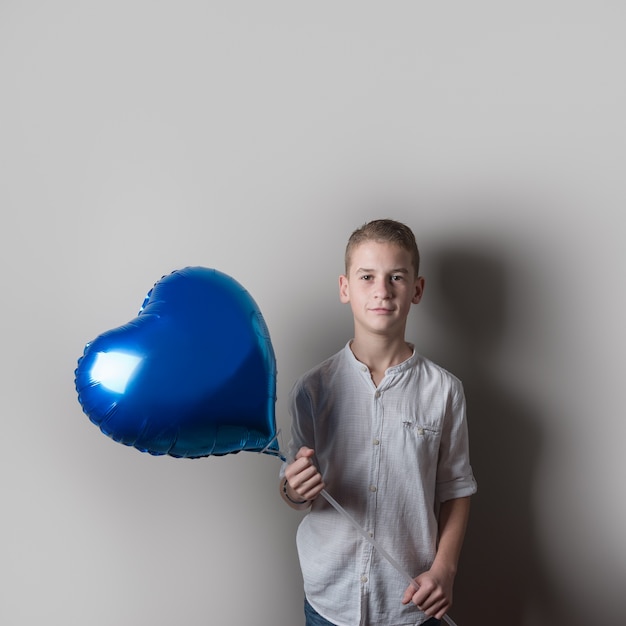 Ragazzo carino con palloncino a forma di cuore su sfondo luminoso Concetto di amore