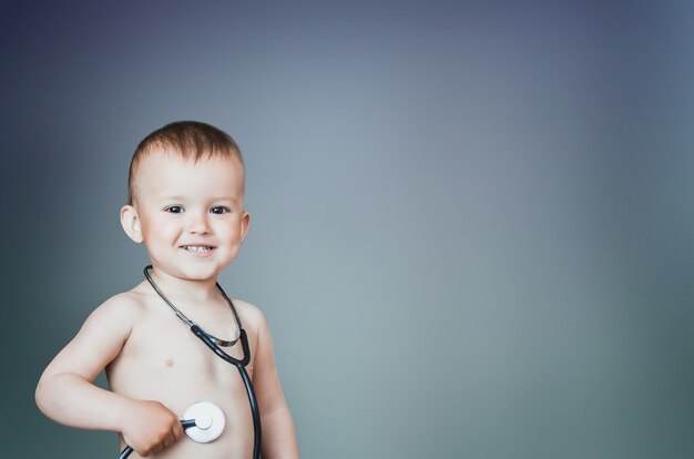 Ragazzo carino con stetoscopio, come un giovane medico su sfondo blu