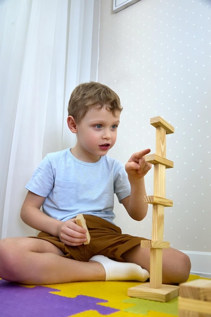 Ragazzo carino in abiti casual che giocano con i blocchi di legno