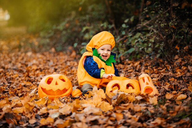 Ragazzo carino in costume da zucca tra zucche intagliate