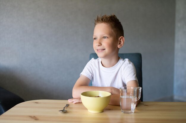 Ragazzo carino mangia una colazione secca a casa e sorride