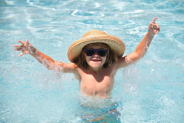 Ragazzo carino nell'acqua che gioca con l'acqua Bambino ragazzo nuotare in piscina Sorridente ragazzino carino in occhiali da sole in piscina in una giornata di sole