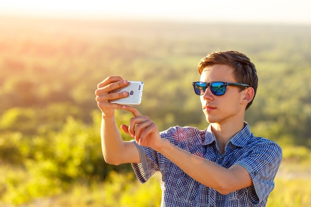 ragazzo carino prende un selfie al telefono sotto il sole