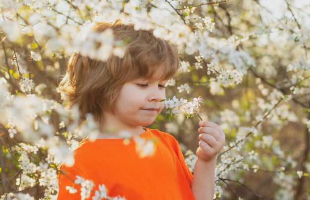 Ragazzo carino primavera nel parco fiorito sorridente albero in fiore all'aperto bambino in giardino