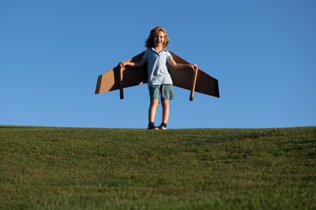 Ragazzo carino sognatore che gioca con un aeroplano di cartone Infanzia Fantasia fantasia Bambino felice che gioca all'aperto