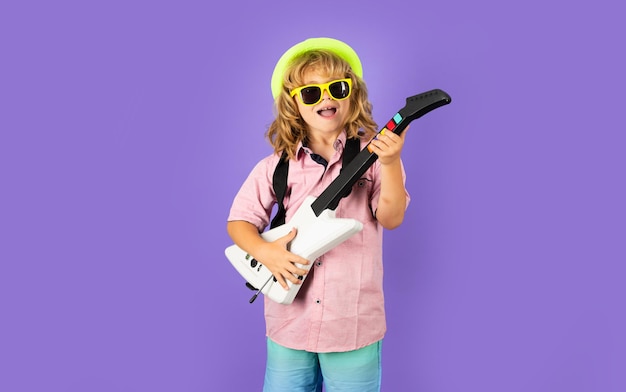 Ragazzo carino suona la chitarra elettrica con occhiali divertenti Divertente bambino musicista hipster che suona la chitarra