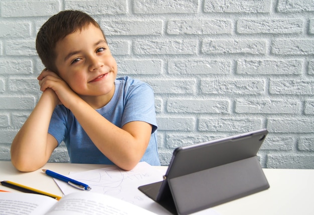 Ragazzo caucasico allegro del bambino che per mezzo del computer portatile. Istruzione domiciliare, apprendimento a distanza, istruzione online