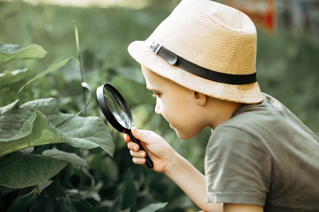 Ragazzo caucasico che esplora l'ambiente naturale con una lente d'ingrandimento