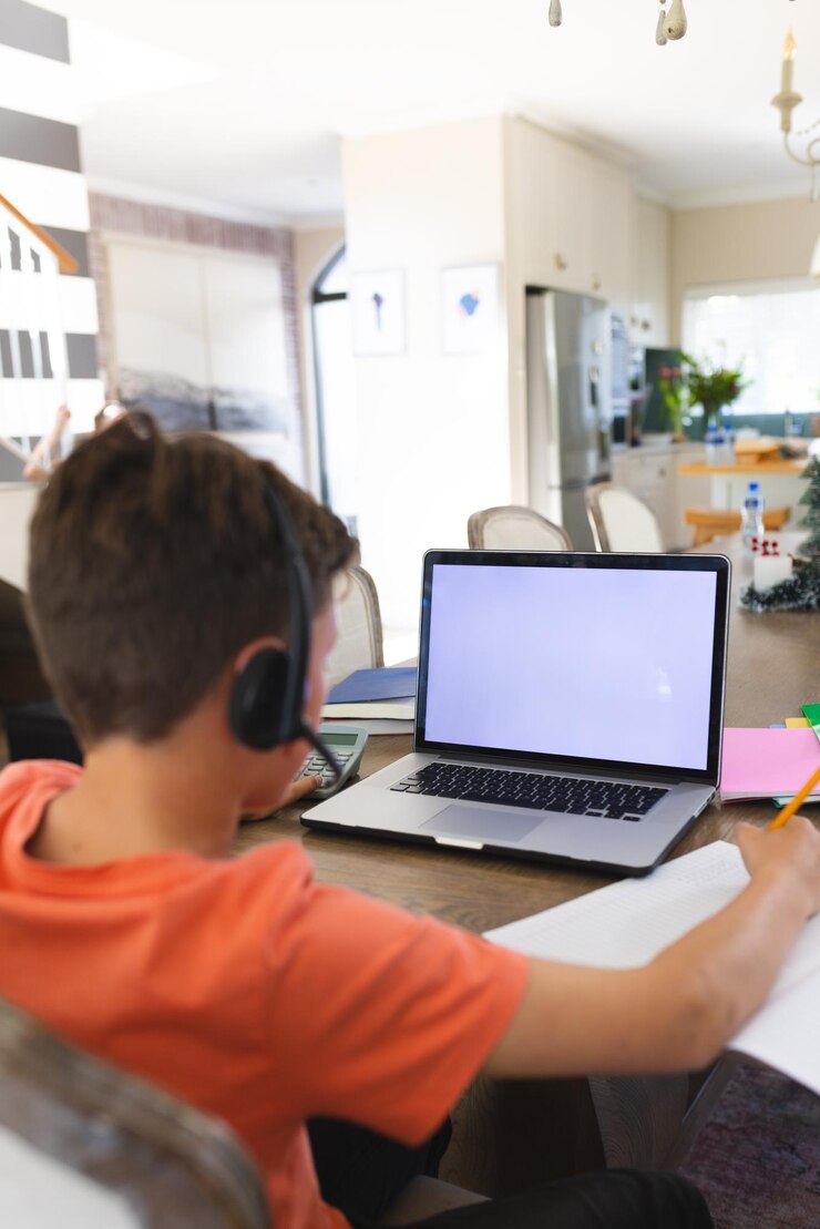 Foto ragazzo caucasico che impara e utilizza il computer portatile con lo spazio della copia e la cuffia