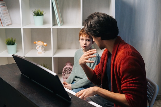 Ragazzo caucasico che suona il sintetizzatore a casa durante il concetto di lezione di educazione musicale