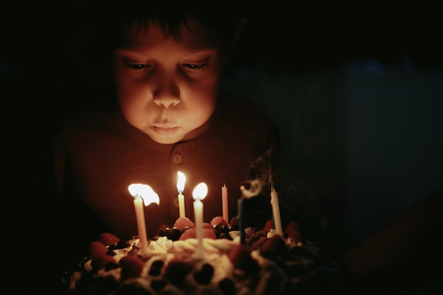 Ragazzo caucasico sveglio che fa saltare in aria le candeline pn torta di compleanno