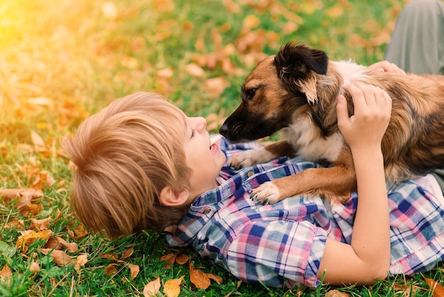 Ragazzo che abbraccia un cane e si diverte nel parco cittadino autunnale