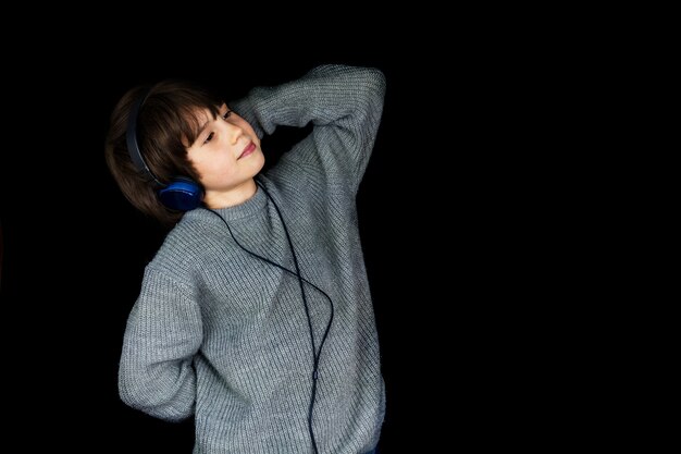 Ragazzo che ascolta la musica sul lettore con le cuffie sul nero