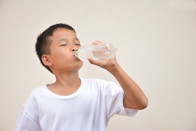 Ragazzo che beve acquaSfondo grigio cemento