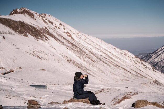 Ragazzo che beve caffè seduto in alta montagna