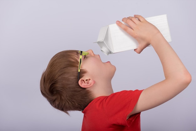 Ragazzo che beve latte o succo dal pacchetto sfondo bianco Copia spazio Modello Mockup