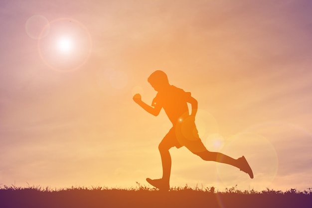 Ragazzo che corre sul campo contro un cielo nuvoloso durante il tramonto