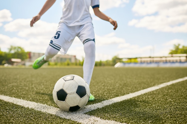 Ragazzo che dà dei calci alla palla sul campo di football americano