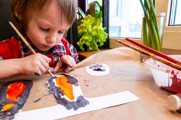 Ragazzo che disegna le orecchie di un coniglietto pasquale fatto a mano in cartone Preparazione per la celebrazione delle vacanze di Pasqua