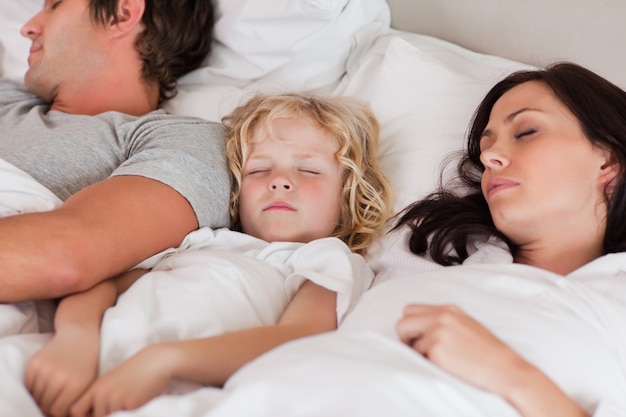 Ragazzo che dorme tra i suoi genitori