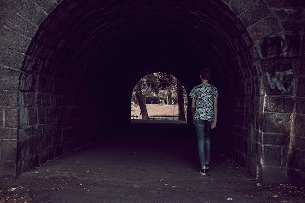 Ragazzo che entra nel tunnel di pietra nel parco