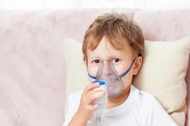 Ragazzo che fa inalazione con un nebulizzatore a casa