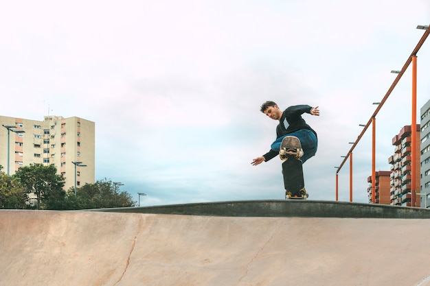 Ragazzo che fa skateboard con uno snakeboard in uno skatepark in una giornata di cielo azzurro e limpido Copia spazio