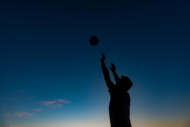 Ragazzo che fa sport con la palla sulla spiaggia in piena estate tramonto sulla costa brasiliana