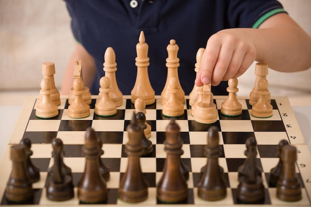 Ragazzo che gioca a scacchi nella stanza Piccolo bambino intelligente che pensa mentre gioca a scacchi a casa