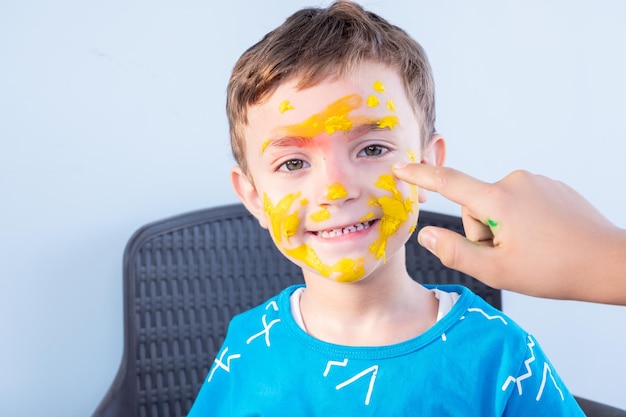 Ragazzo che gioca con i colori usando le mani e il viso