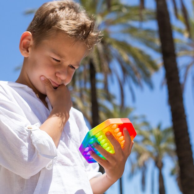 Ragazzo che gioca con il giocattolo arcobaleno anti stress pop it all'aperto